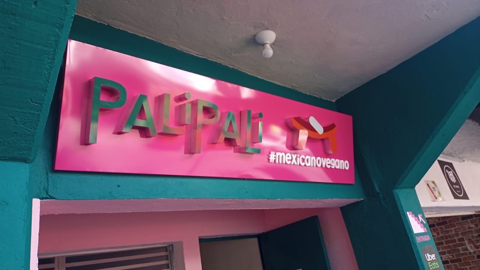 Letras 3D metálicas con acabado espejo sobre panel rosa en la fachada del restaurante Pali Pali
