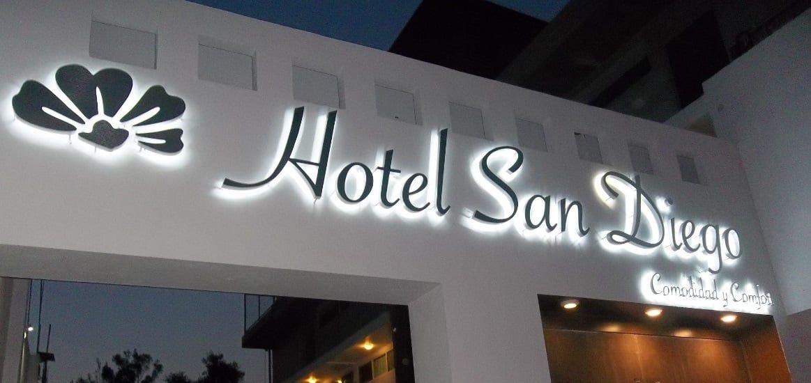 Letras de aluminio cepillado con retroiluminación LED blanco cálido y logotipo floral en la fachada del Hotel San Diego