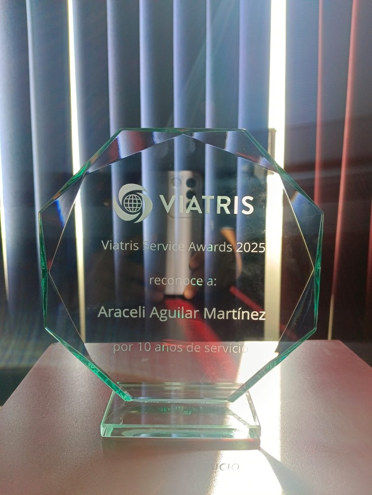 Reconocimiento octagonal de cristal biselado con grabado esmerilado de Viatris Service Awards 2025, sobre base de cristal